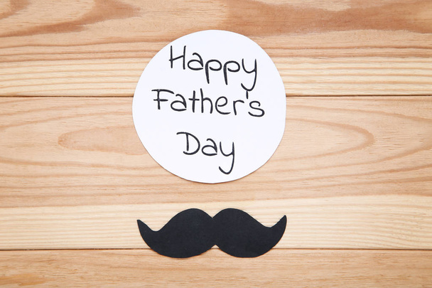 Text Happy Fathers Day with black mustache on wooden table - Fotó, kép