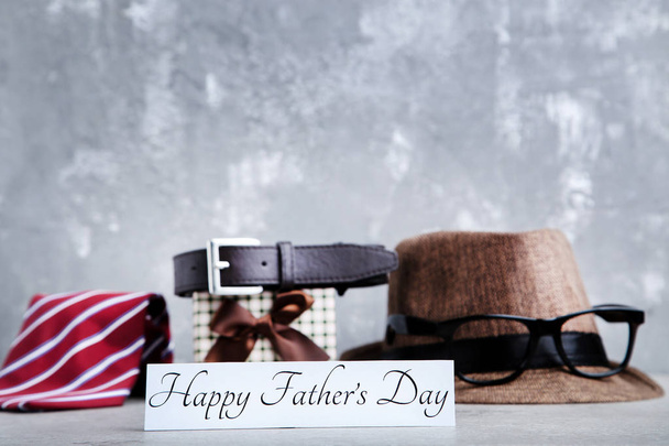 Text Happy Fathers Day with necktie, belt, hat and glasses on gr - Фото, изображение