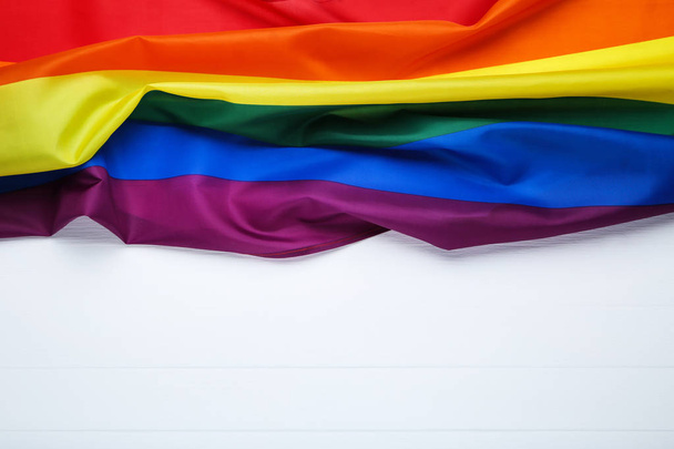 Rainbow flag on white wooden table - Фото, изображение