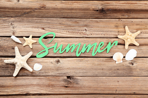 Word Summer with seashells on brown wooden table - Fotó, kép
