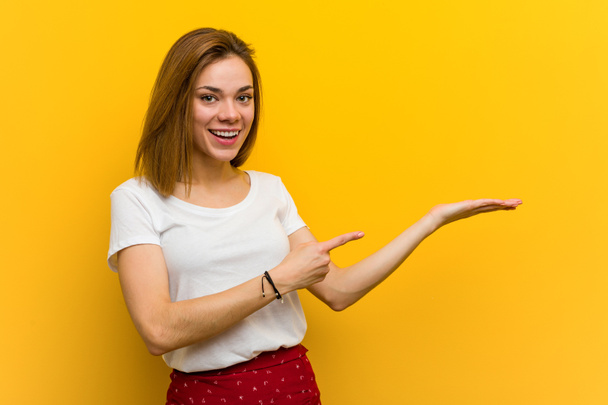 Young natural caucasian woman excited holding a copy space on palm. - Photo, Image