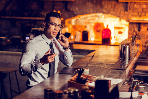 Businessman calling his partner while working remotely in the bar - Фото, изображение