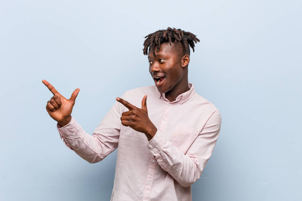 junger unternehmerischer schwarzer Mann zeigt mit den Zeigefingern auf einen Kopierraum und drückt damit Begeisterung und Wunsch aus. - Foto, Bild