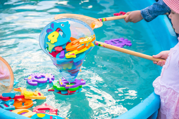 Educational water game for children. Fish in the form of letters of numbers and images of animals and a net for fishing. Fun for kids - Photo, Image