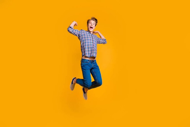 Full length body size view portrait of his he nice attractive cheerful cheery optimistic overjoyed guy in checked shirt having fun time isolated over bright vivid shine yellow background - Foto, afbeelding