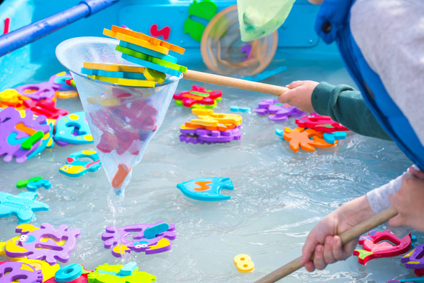 Wasserspiel für Kinder. Fische in Form von Buchstaben aus Zahlen und Bildern von Tieren und einem Netz zum Fischen. Spaß für Kinder - Foto, Bild