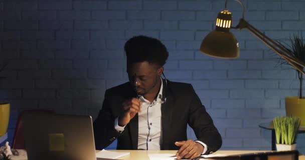 Young stressed businessman trying to keep calm in the workplace and returns to work. Tired office worker working on the laptop at late night. Workaholic, the deadline concept. - Materiaali, video