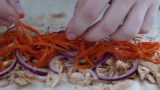 Cucinare kebab doner. Le mani delle donne spargono carote marinate su cipolle rosse e carne di pollo bollita
. - Filmati, video