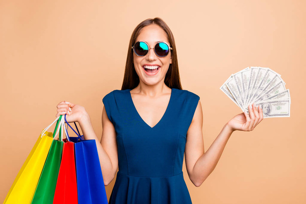 Portrait of her she nice-looking attractive lovely groomed cheerful cheery glad straight-haired lady holding in hands bags with new look clothing 100 atm income isolated on beige background - Фото, зображення