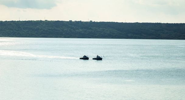 dos barcos de pesca a motor son de arrastre en el lago, campos verdes en el fondo
 - Foto, imagen