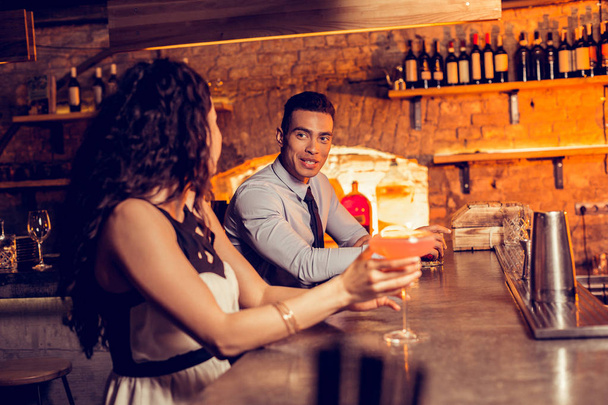 Curly woman drinking cocktail in bar talking to man - Foto, Imagen