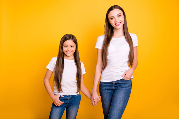 Close up photo two beautiful her she diversity lady different age best buddies hold hands arms go secondary highschool wear casual white t-shirts jeans denim clothes isolated yellow bright background - Fotografie, Obrázek