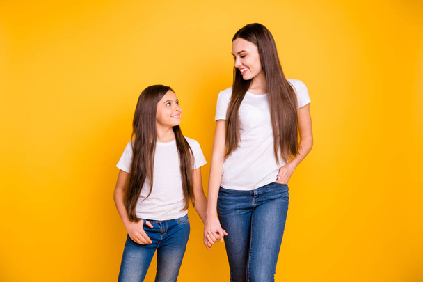Close up photo two beautiful her she diversity lady different age hold hands arms go secondary highschool speak communicate wear casual white t-shirts jeans denim isolated yellow bright background - Foto, Imagem