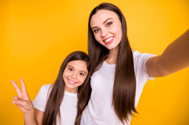 Close up photo beautiful funny her she diversity lady different age make take selfies show v-sign positive mood say hi parents wear casual white t-shirts jeans denim isolated yellow bright background - Foto, afbeelding