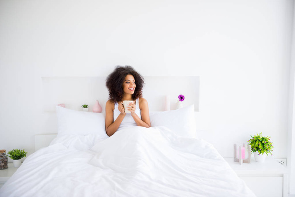 Close up photo beautiful amazing she her dark skin lady weekend vacation flirty hands arms hold hot beverage break pause look side white sleeping wear lying big large bedroom homey house indoors - Foto, Imagem