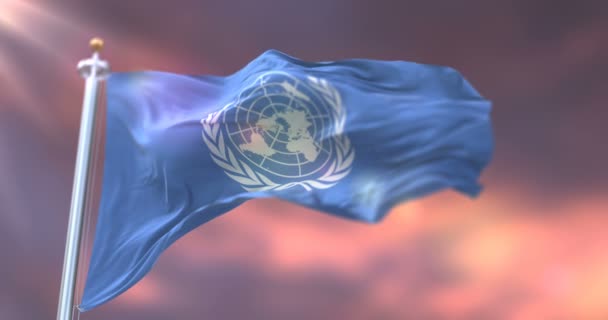 Vlag van de Verenigde Naties zwaaiend naar wind in slow bij zonsondergang, loop - Video
