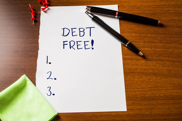Text sign showing Debt Free. Conceptual photo does not owning any money or things to any individual or companies Blank stationary paper wooden table fountain pen cloth rag pins to fix. - Photo, Image