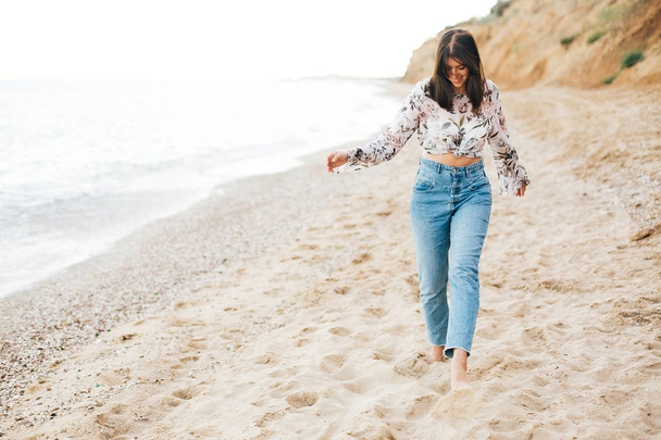 Stylish hipster girl running on beach at sea and smiling. Happy  - 写真・画像
