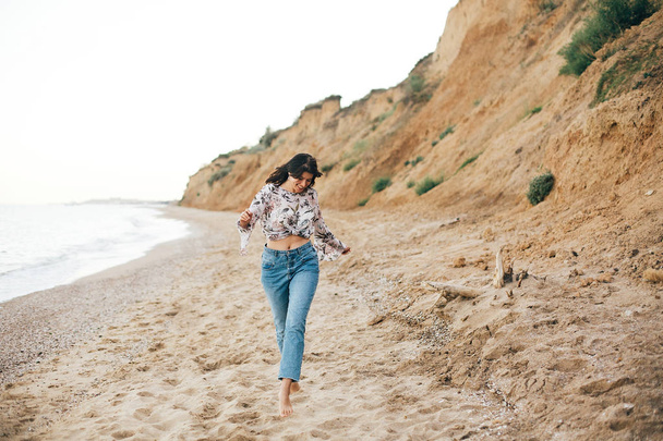 Elegante chica hipster corriendo en la playa en el mar y sonriendo. Feliz.
  - Foto, Imagen