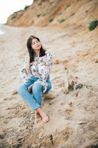 Stylish hipster girl sitting on beach at sea. Happy fashionable  - Foto, imagen