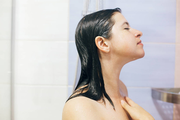若い幸せな女性が自宅やホテルのバスルームでシャワーを浴びています。ビュート - 写真・画像