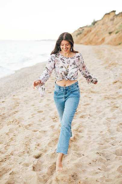 Стильная девушка-хипстер бегает по пляжу на море и улыбается. Счастливый
  - Фото, изображение