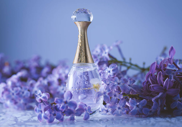 Botella cosmética de cerca con flores lila
 - Foto, Imagen
