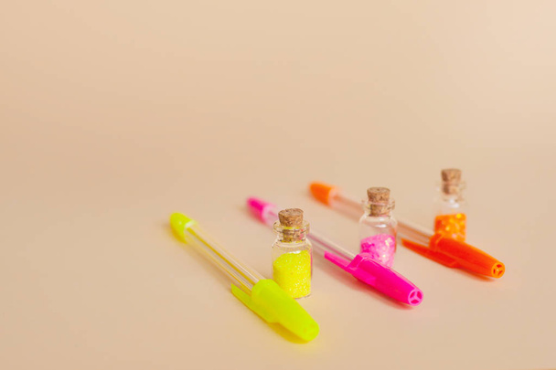 Colorful glitter in bottles and bright neon pens for writing on a natural background - Photo, Image