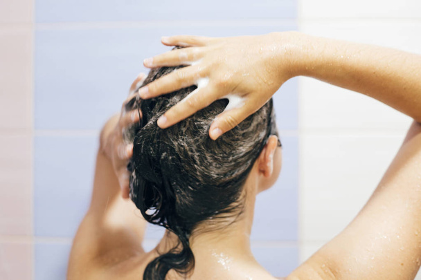 Joven mujer feliz lavándose el cabello con champú, manos con espuma
 - Foto, Imagen