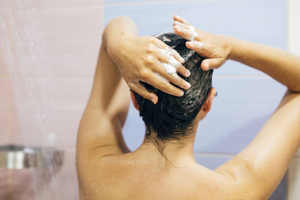 Giovane donna felice lavarsi i capelli con shampoo, mani con schiuma
 - Foto, immagini