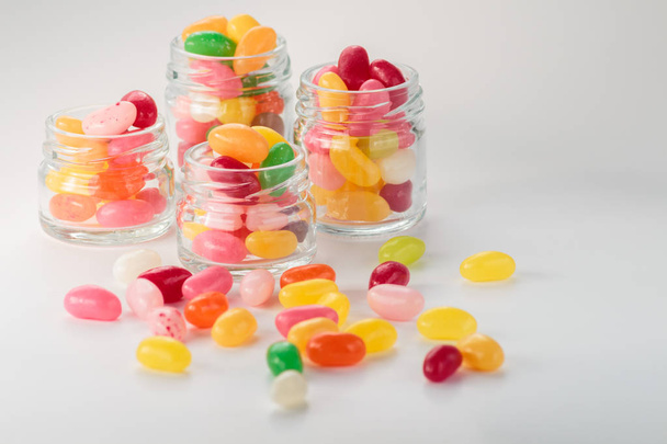Jelly beans in small glass jars on white background - Фото, зображення