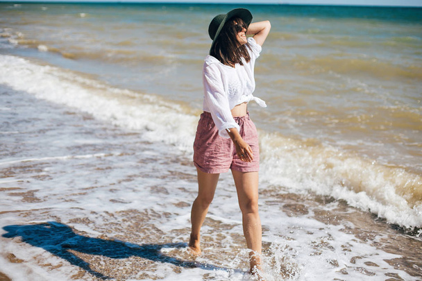 Onnellinen nuori boho nainen kävelee meren aallot aurinkoinen lämmin päivä
 - Valokuva, kuva