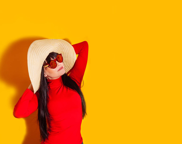 girl straw hat sun sunglasses light shadow tropical yellow orange young woman background red t-shirt - Photo, Image
