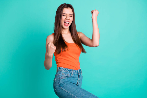 Close up side profile photo beautiful yelling yeah her she lady arms hands fists raised champion football competition wear casual orange tank-top jeans denim isolated bright teal turquoise background - Photo, image