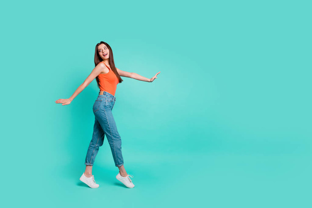 Full length side profile body size photo beautiful her she lady wondered look empty space easy-going weekend walking park wear orange tank-top jeans denim isolated bright teal turquoise background - Foto, imagen