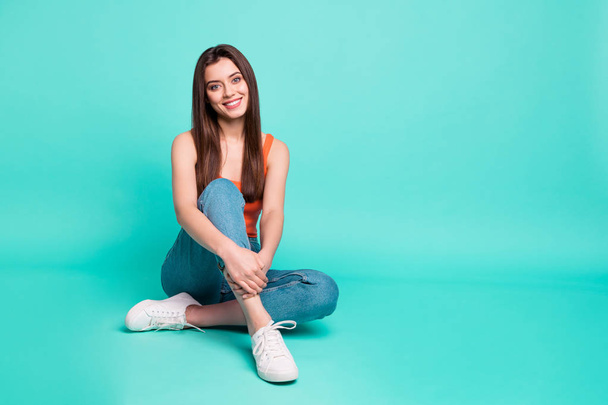 Full length body size photo beautiful her she lady easy-going weekend vacation sitting floor wondered perfect teeth wear casual orange tank-top jeans denim isolated bright teal turquoise background - Foto, afbeelding