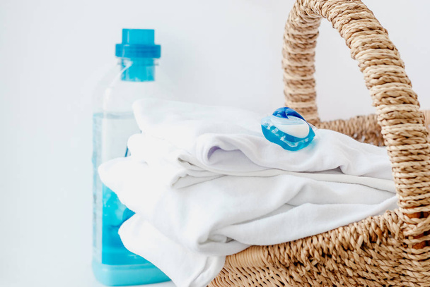 Pila de ropa y vainas de lavandería en una cesta en casa
 - Foto, imagen