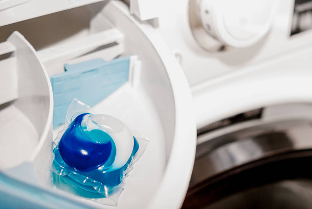 Laundry blue capsule in a washing machine - Foto, Bild
