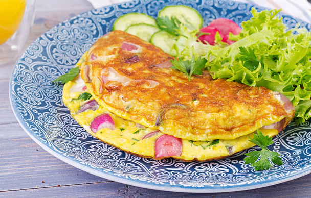 Breakfast. Omelette with radish, red onion and fresh salad on blue plate.  Frittata - italian omelet. - Photo, Image