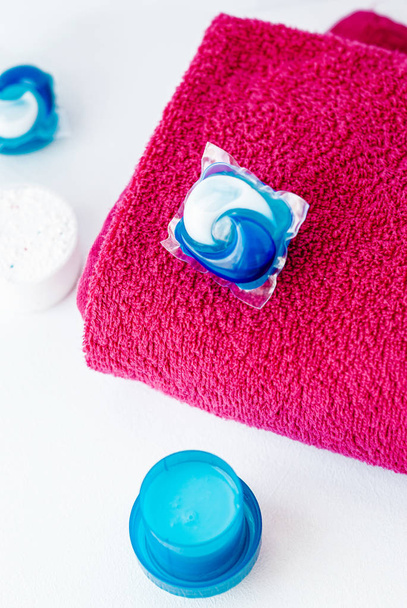 Lavar cápsulas de detergente y toalla rosa
 - Foto, imagen
