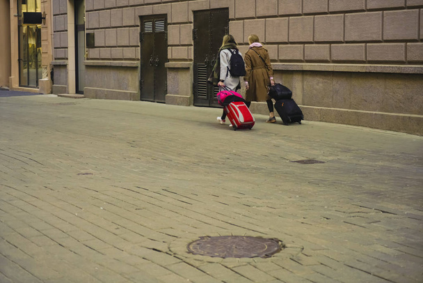 Two girls walking  on the sidewalk with suitcases - Φωτογραφία, εικόνα