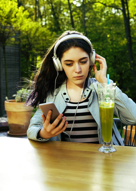 Young pretty woman using smartphone in cafe, drink smoothies  in glass.beautiful girl enjoying a smoothie drink in a cafe and using mobile cell phone. - Φωτογραφία, εικόνα