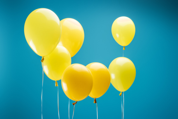 bright yellow festive balloons on blue background - Фото, изображение