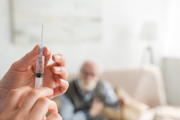 Selective focus of woman hands with syringe on senior man background - Photo, Image
