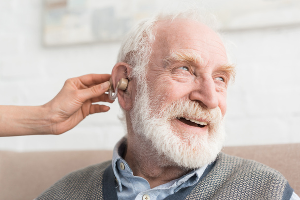 glücklicher grauhaariger Mann mit Hörgerät, der wegsieht - Foto, Bild