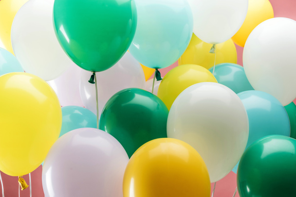 close up view of bright green, white, yellow and blue decorative balloons on pink background - Φωτογραφία, εικόνα