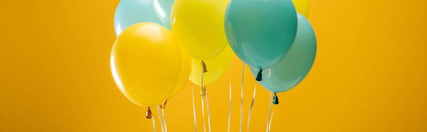 Sváteční dekorativní modré a žluté balónky na žlutém pozadí, panoramatický záběr - Fotografie, Obrázek