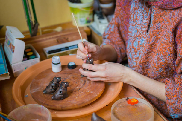 Professional woman potter painting ceramic souvenir penny whistle in pottery - Фото, зображення