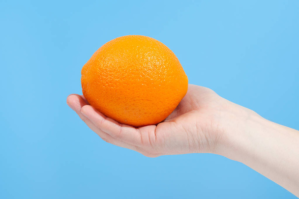 Hand holding organic delicious orange Isolated on blue Backgroun - Fotoğraf, Görsel