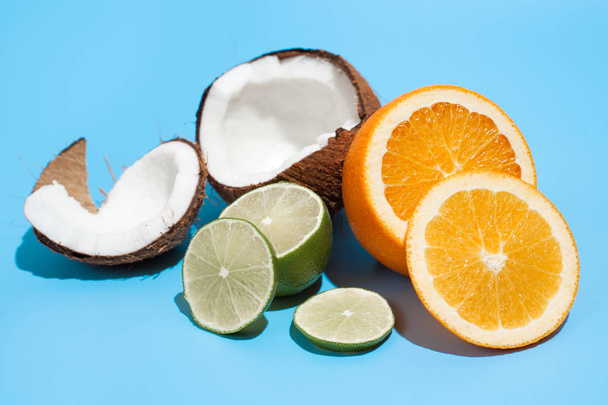 Fresh juicy orange, coconut and green lime isolated on blue back - Photo, Image